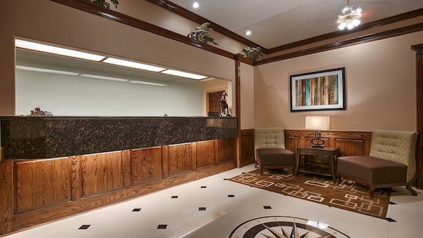 Un hall d’entrée avec un comptoir de réception, deux fauteuils, une table basse, un tableau et un tapis décoratif.