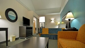 Une chambre d’hôtel équipée d’un téléviseur à écran plat, d’un canapé, d’une table et d’une lampe.
