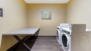 A laundry room with a washing machine, dryer, and a bench.