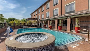 Relax by the pool, surrounded by a mosaic-tiled deck and lounge chairs, with a hot tub and covered seating area nearby.