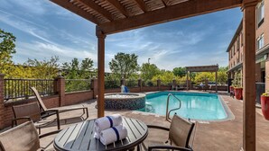 A covered outdoor area with a pool, lounge chairs, and a table with towels. - Best Western Plus DFW Airport Suites (Irving)