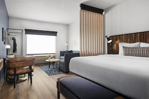 A modern hotel room with a large bed, a seating area with a chair and table, a desk with a lamp, and a window with curtains. - Best Western Plus DFW Airport Suites (Irving)