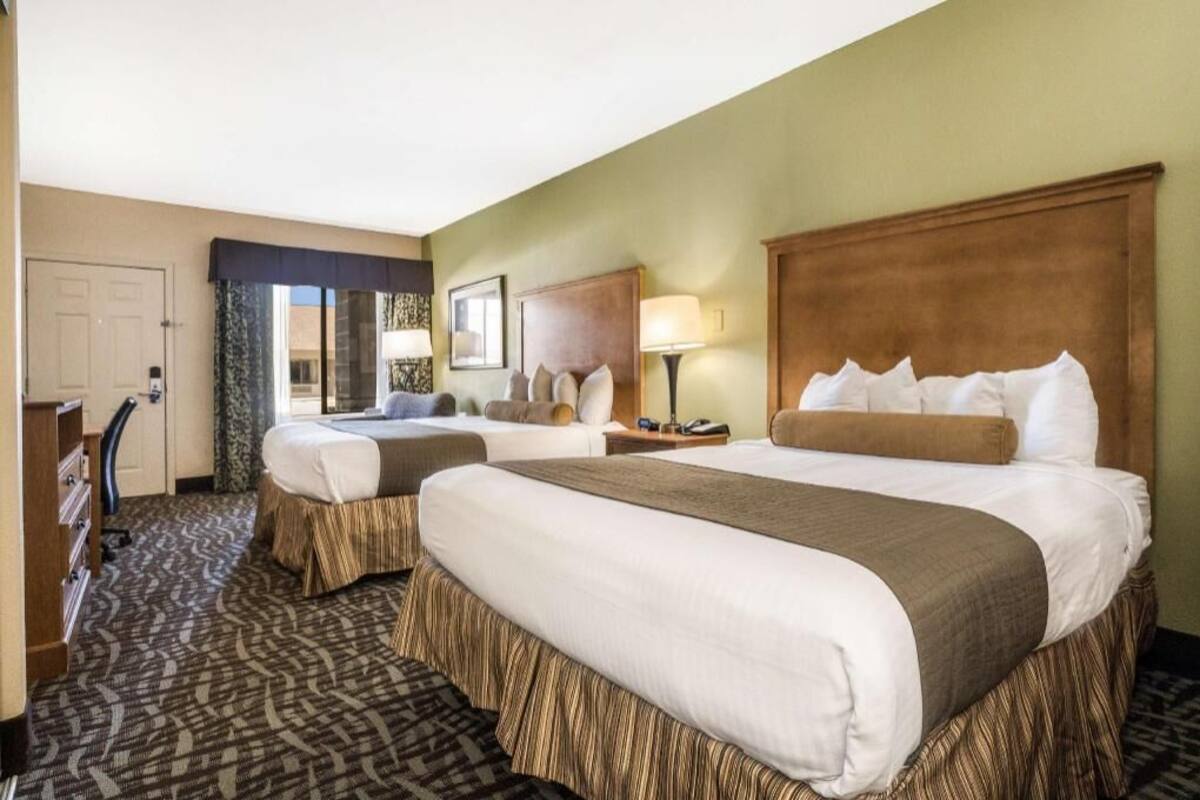 Een hotelkamer met twee bedden, een bureau, een stoel en een groot raam.
