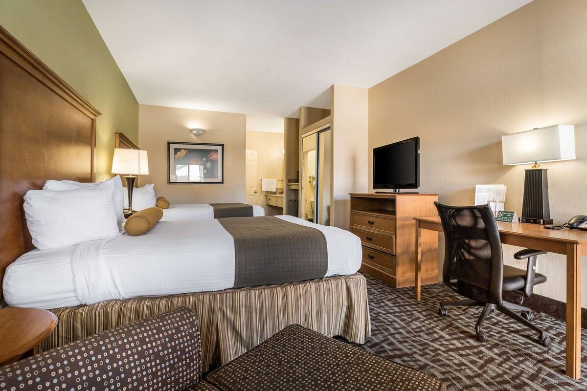 Een hotelkamer met een groot bed, een bureau, een stoel, een televisie en een lamp.