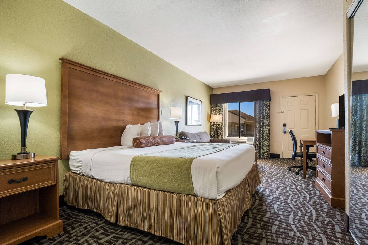 Een hotelkamer met een groot bed, een bureau, een stoel en een kast.