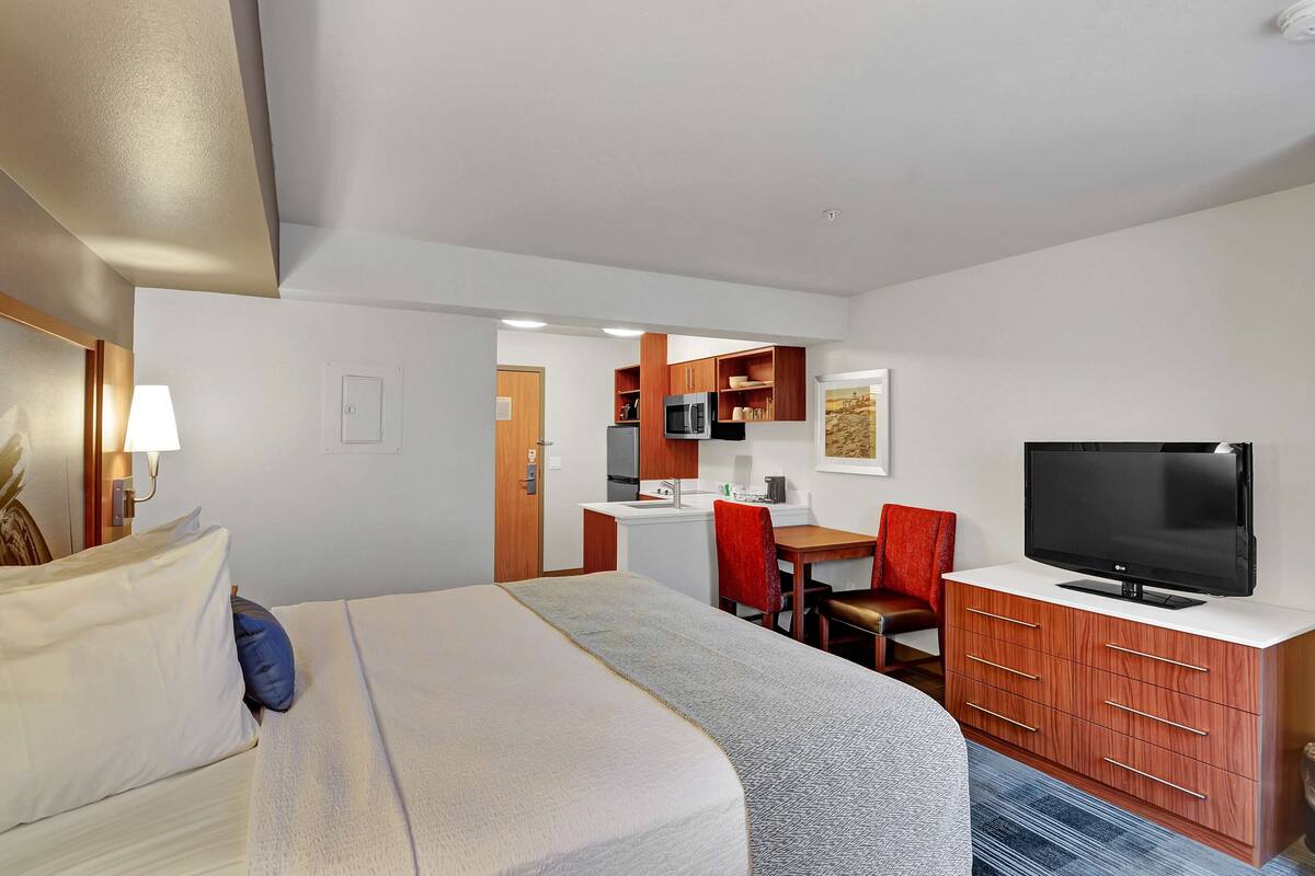 Une chambre d’hôtel équipée d’un lit, d’une télévision, d’un bureau et d’une kitchenette.