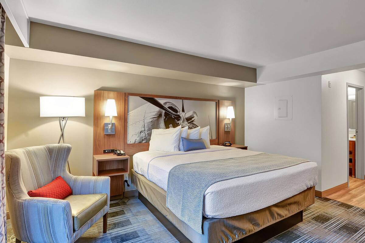 Une chambre d’hôtel avec un grand lit, une chaise, un bureau et une table de chevet.