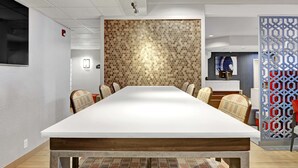 Une salle de conférence avec une longue table, des chaises, un mur orné de motifs et un paravent décoratif.