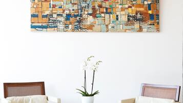 A room with two wooden chairs, a small table, and a large abstract painting on the wall.