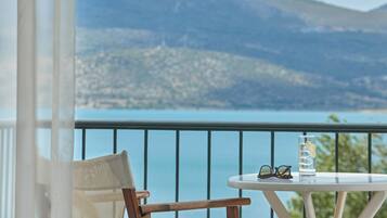 A balcony with a table, a chair, a glass of water, and a pair of sunglasses.