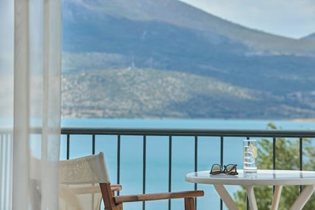 A balcony with a table, a chair, a glass of water, and a pair of sunglasses.