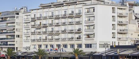 A multi-story hotel with balconies, a waterfront view, and outdoor seating areas.