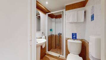 Un baño con ducha, lavamanos e inodoro.