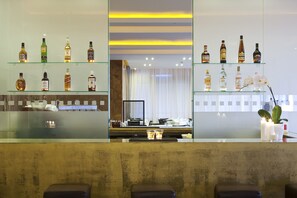 A bar area with shelves of liquor bottles, a mirror, and a seating area with a bench. - Lucy Hotel (Chalcis)