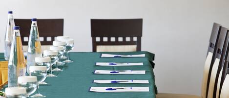Una mesa de conferencias con documentos, una botella de agua y vasos preparados para una reunión.