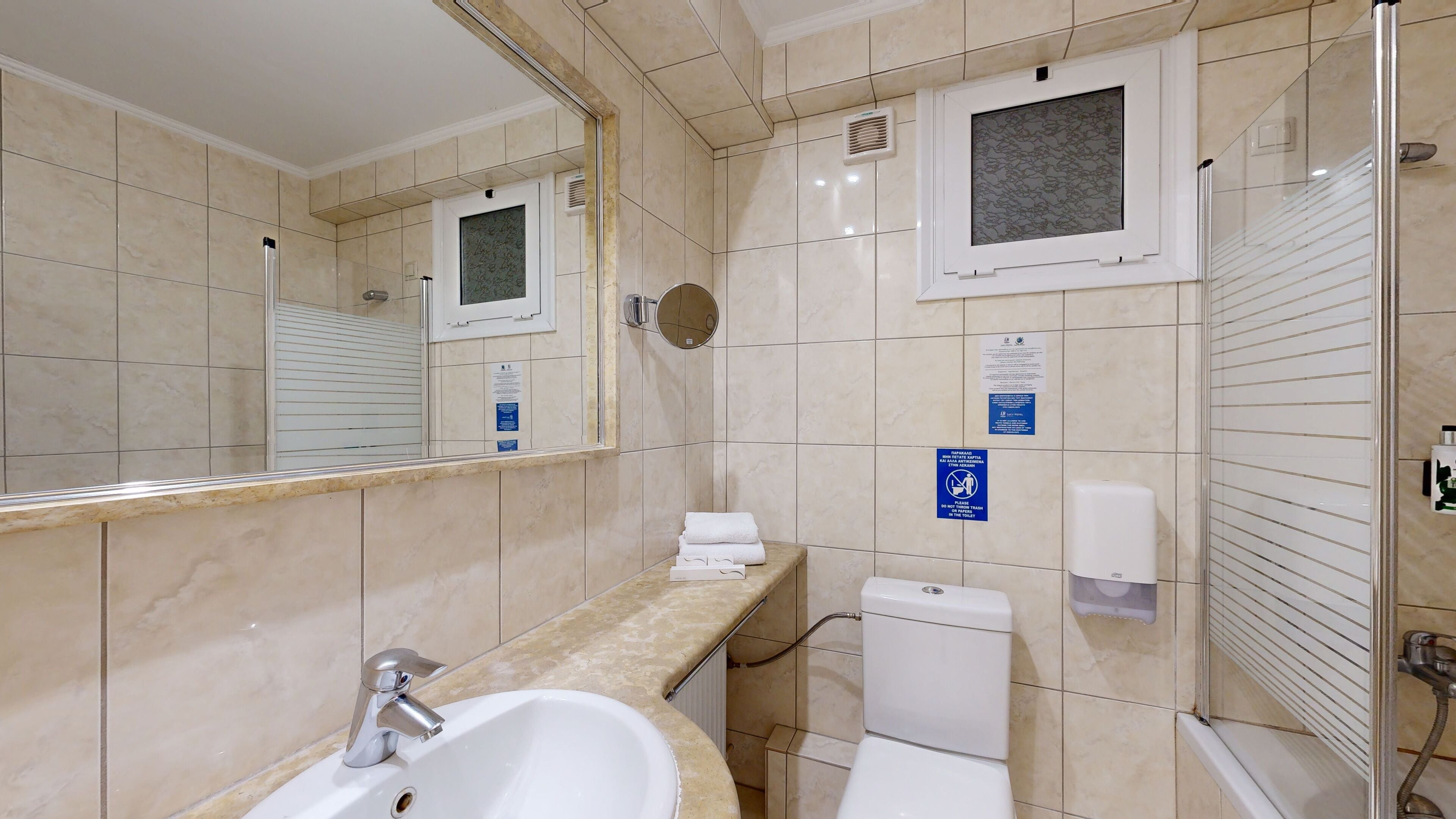 A bathroom with a sink, mirror, toilet, and shower.