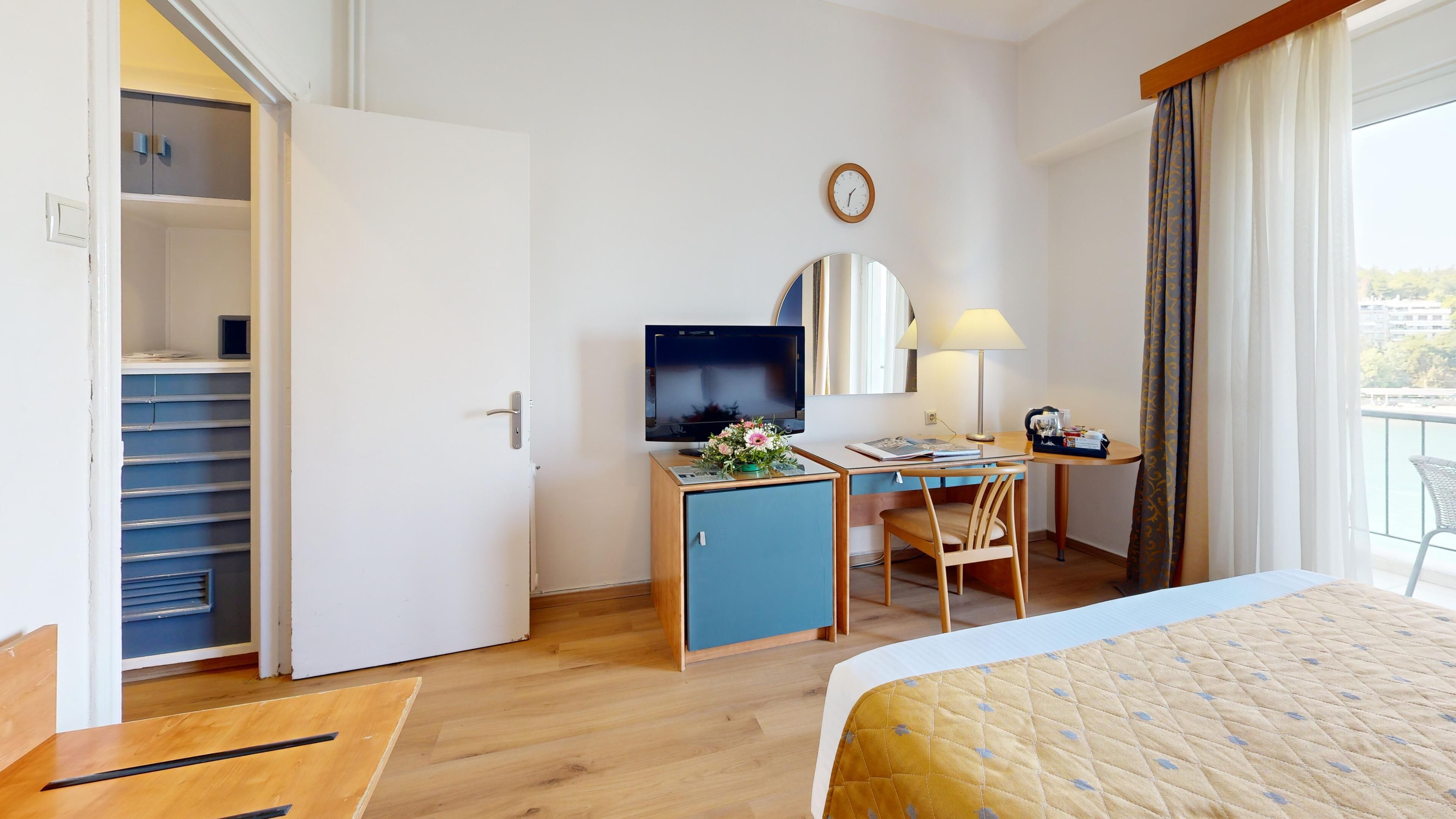 Une chambre d’hôtel équipée d’un lit, d’un bureau, d’une chaise, d’une télévision et offrant une vue sur l’extérieur.