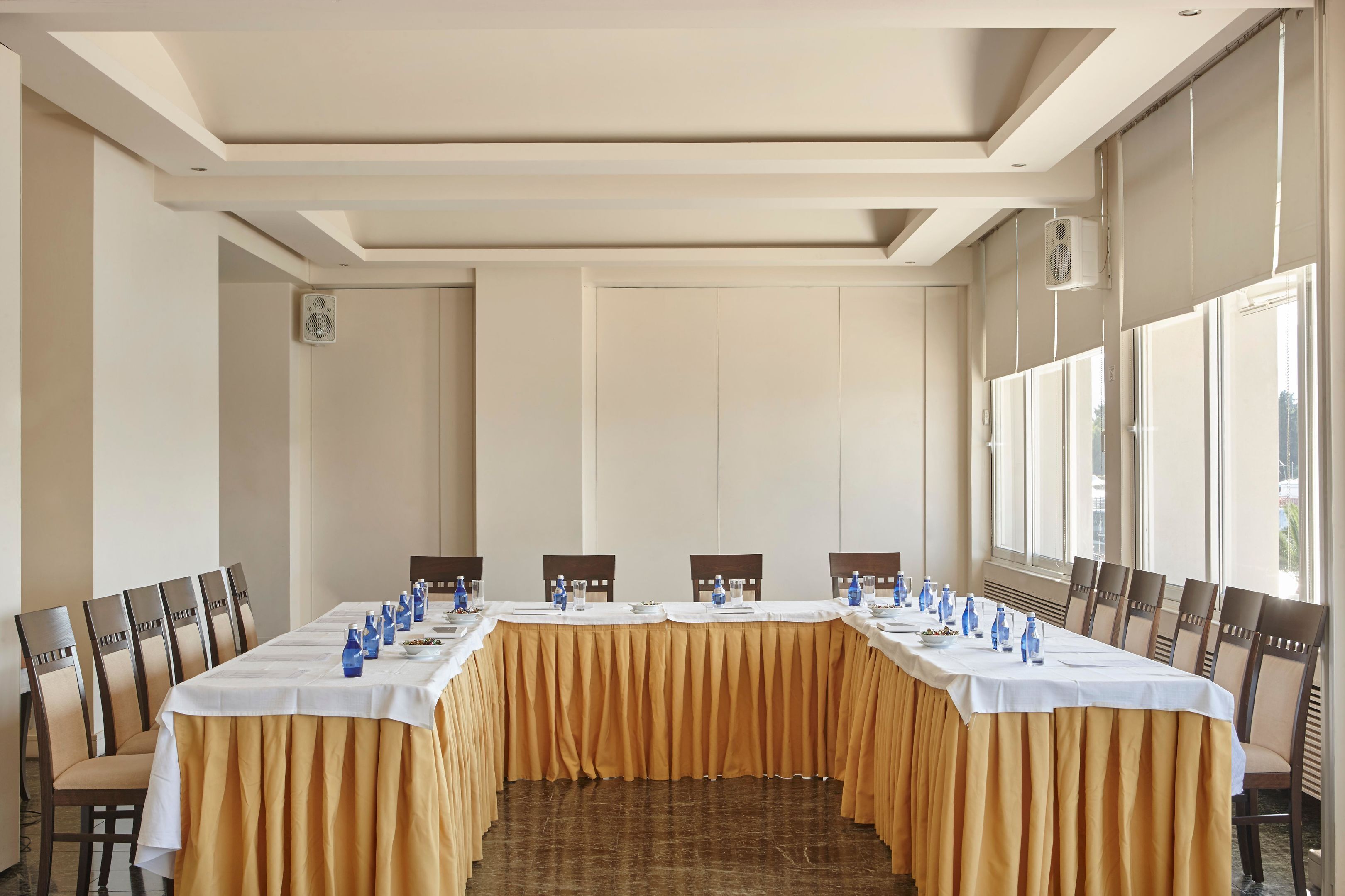 Un salón de conferencias con una larga mesa, sillas y un mantel amarillo.