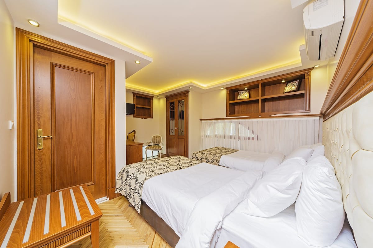 A bedroom with a large bed, bedside tables, a wardrobe, and built-in shelves.