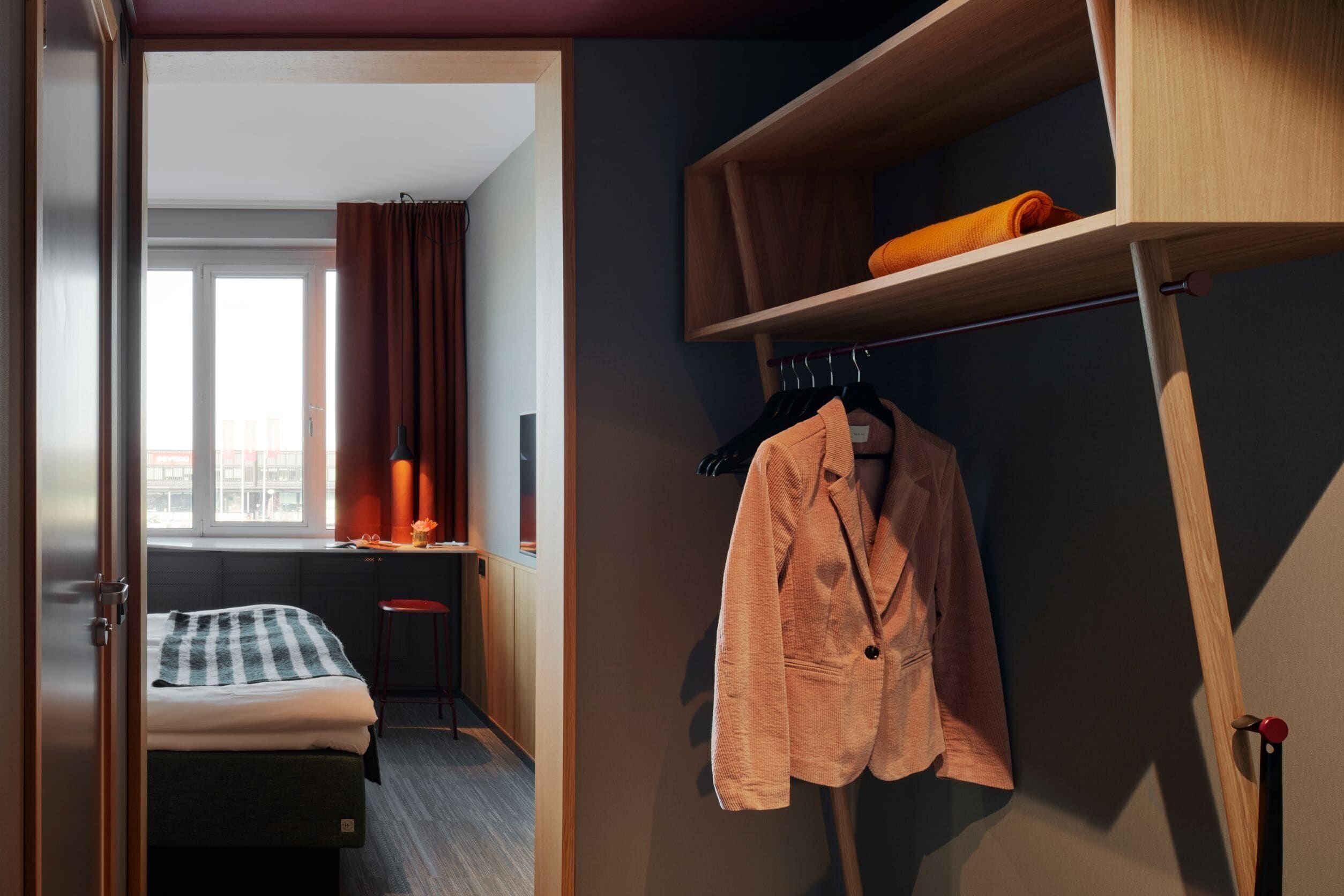 A hotel room with a bed, a desk, and a wardrobe.