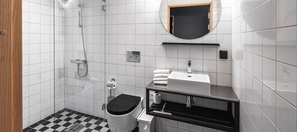 A modern bathroom with white tiles, a black and white checkered floor, a toilet, a sink with a mirror above it, and a shower area.