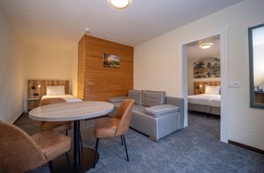 Ein Hotelzimmer mit einem runden Tisch, zwei Sofas, einem Bett und einem Gemälde an der Wand.