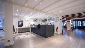 A hotel reception area with a reception desk, a clock, and a modern interior design. - Fletcher Hotel De Witte Brug (Lekkerkerk)
