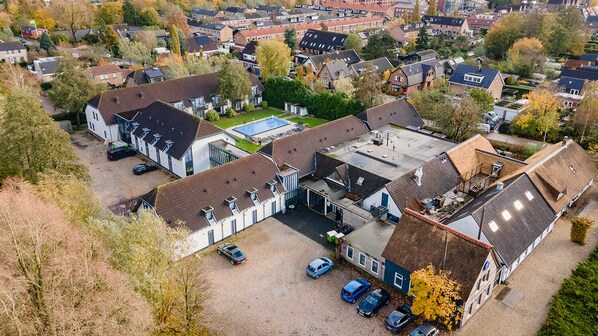 An aerial view of a residential area with houses, a swimming pool, and a parking lot.