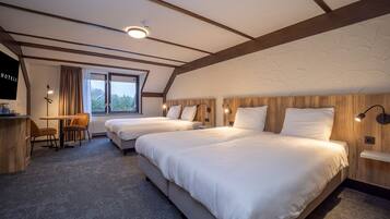 Een hotelkamer met twee bedden, een bureau, een stoel, een televisie en een raam met gordijnen.