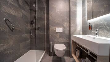 Un baño moderno con ducha de vidrio, inodoro blanco y tocador con espejo.