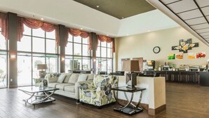 Eine geräumige Lobby mit einer Couch, Sesseln und einer Kaffeestation.