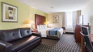 A hotel room with a bed, a sofa, a desk, and a television.