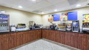 A breakfast area with a coffee machine, waffle maker, and a refrigerator.