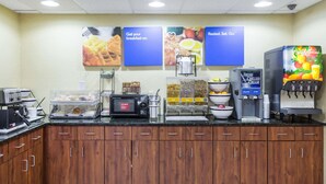 A breakfast bar with a coffee machine, microwave, and food display.