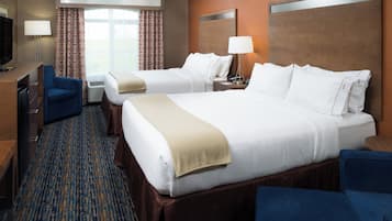 A hotel room with two beds, a desk, a chair, a TV, and a window with curtains.