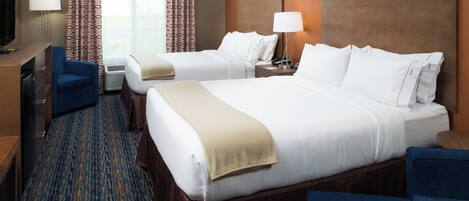A hotel room with two beds, a desk, a chair, a TV, and a window with curtains.