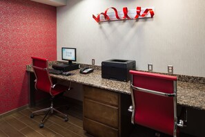 Habitación de hotel con escritorio, dos sillas rojas, una computadora e impresora.
