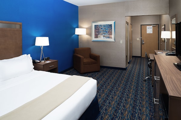 A hotel room with a large bed, a chair, a desk, a lamp, and a painting on the wall. - Holiday Inn Express Rocklin - Galleria Area by IHG (Rocklin)