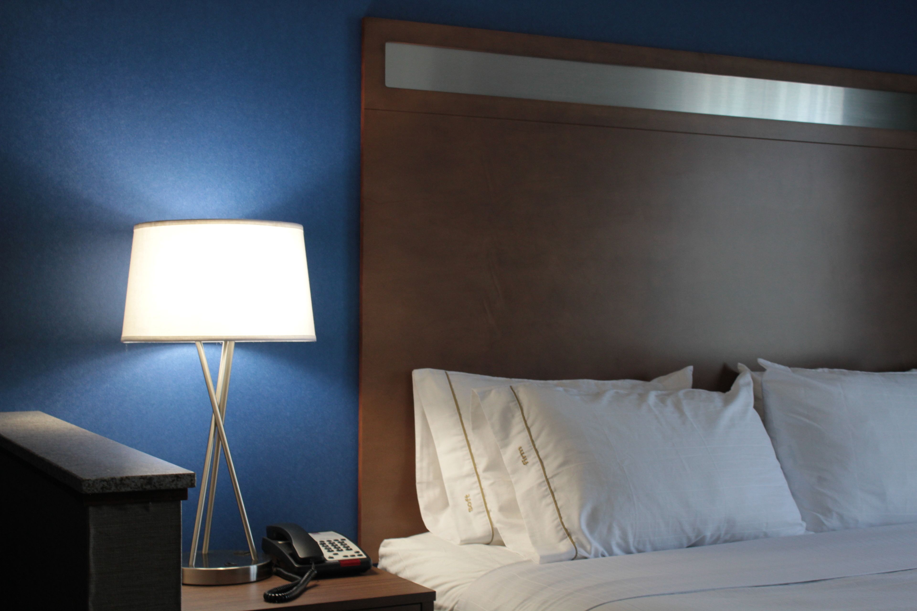 A hotel room with a bed, a bedside lamp, a telephone, and a nightstand.