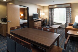 A hotel room with a wooden dining table, a separate desk with a computer, a bed, a bathroom, and a large window with patterned curtains. - Holiday Inn Express Rocklin - Galleria Area by IHG (Rocklin)