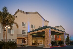 A hotel with a stone facade, a covered entrance, and a parking lot. - Holiday Inn Express Rocklin - Galleria Area by IHG (Rocklin)