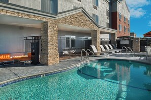 A pool area with lounge chairs and a stone wall. - Holiday Inn Express Rocklin - Galleria Area by IHG (Rocklin)