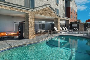 Un área de piscina con sillas de descanso y un muro de piedra.