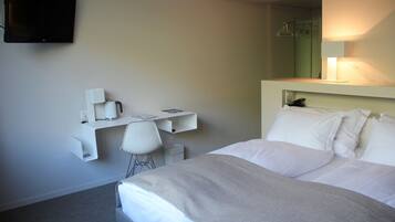 Ein Hotelzimmer mit einem Bett, einem Schreibtisch mit Stuhl, einem Fernseher und einem Spiegel.