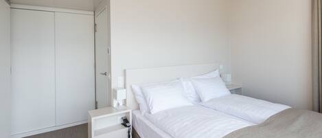 A hotel room with a bed, a nightstand, a wardrobe, and a door.