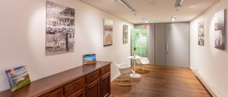 A hallway with wooden flooring, a wooden cabinet, and a white chair.