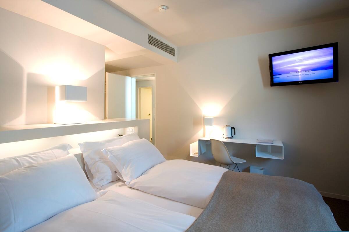 Een hotelkamer met een bed, een aan de muur bevestigde televisie, een koffieapparaat en een stoel.