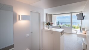 Una habitación de hotel moderna con balcón, escritorio y televisor.