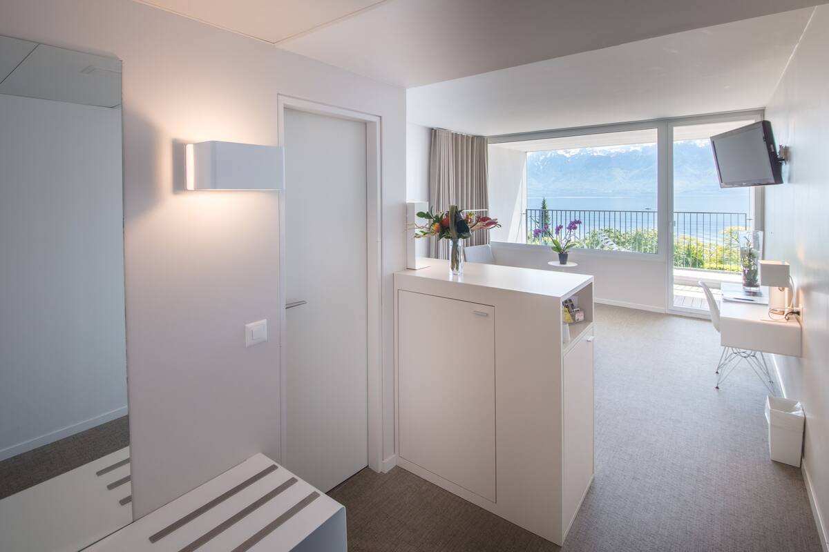 Een moderne hotelkamer met balkon, bureau en televisie.