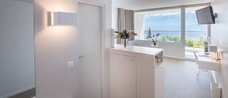 Quarto de hotel moderno com varanda, escrivaninha e televisão.